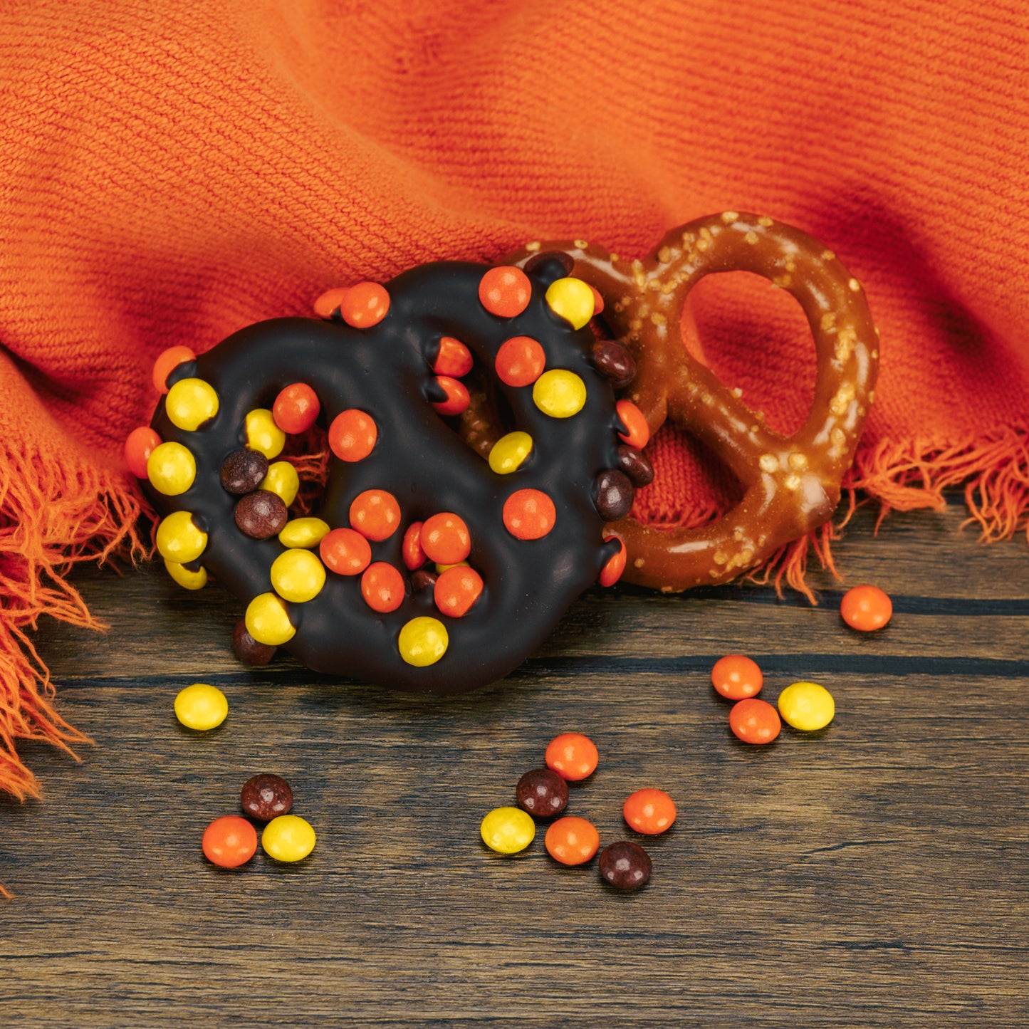 A jumbo pretzel covered in dark chocolate with mini Reese's Pieces sprinkled on top.
