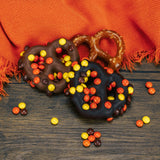 A jumbo pretzel covered in milk or dark chocolate with mini Reese's Pieces sprinkled on top.