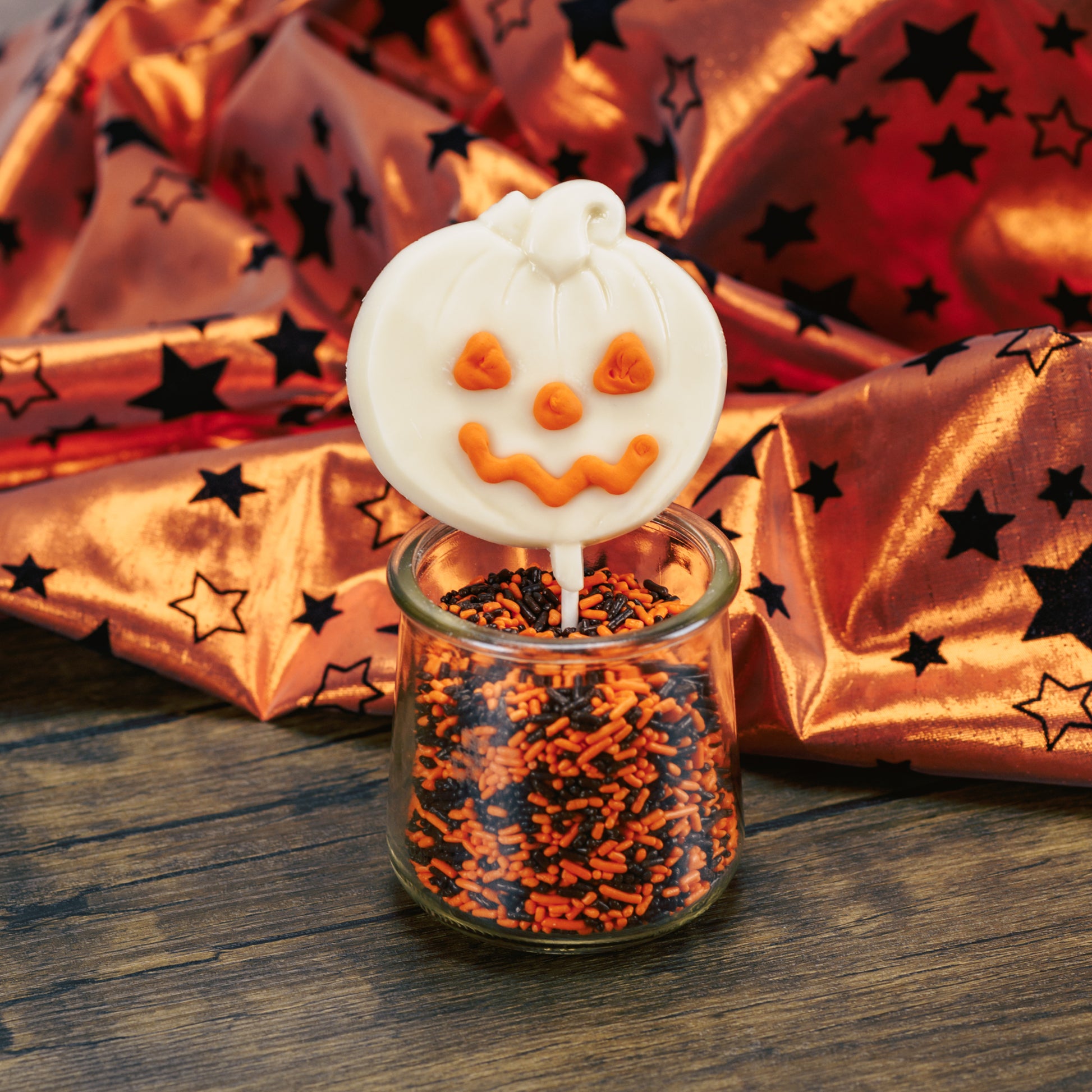 white coating pumpkin on a sucker stick. With orange icing for eyes, nose and smile.
