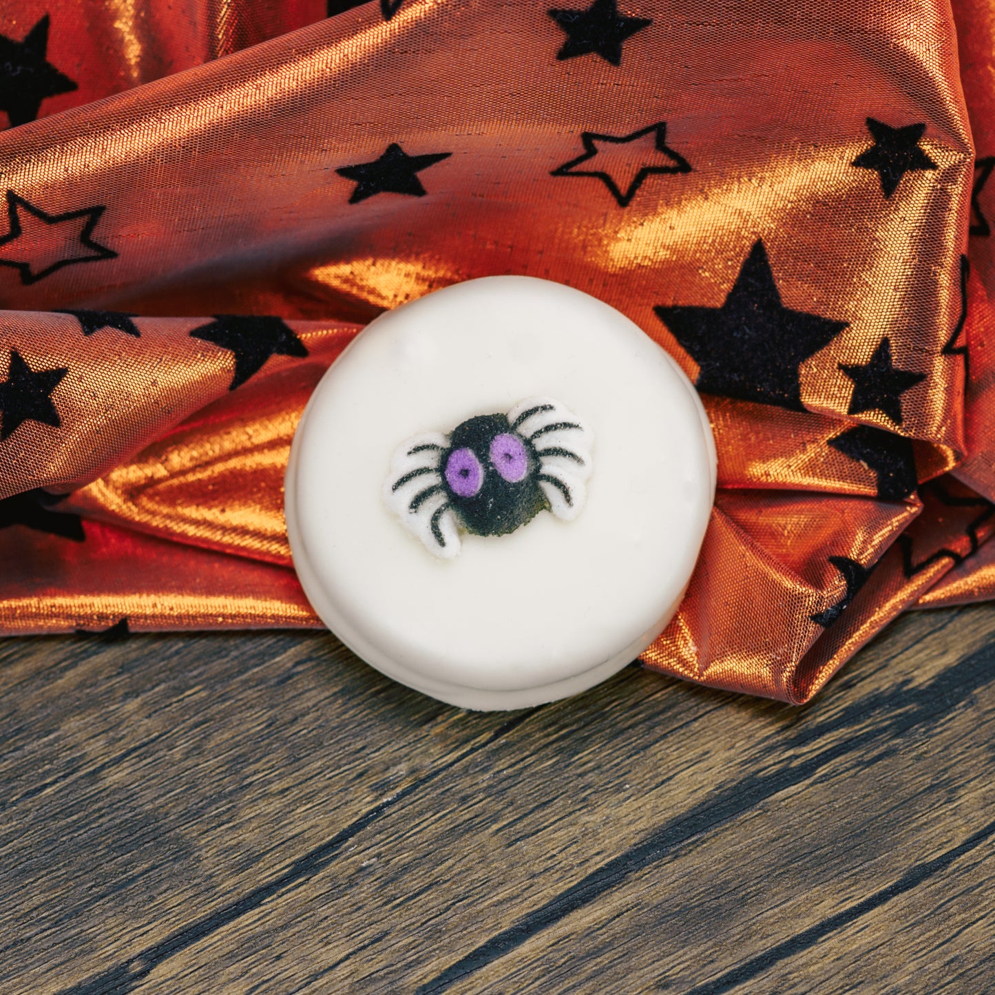 Oreo cookies covered in white coating. Each with a sugar Halloween decoration on top.