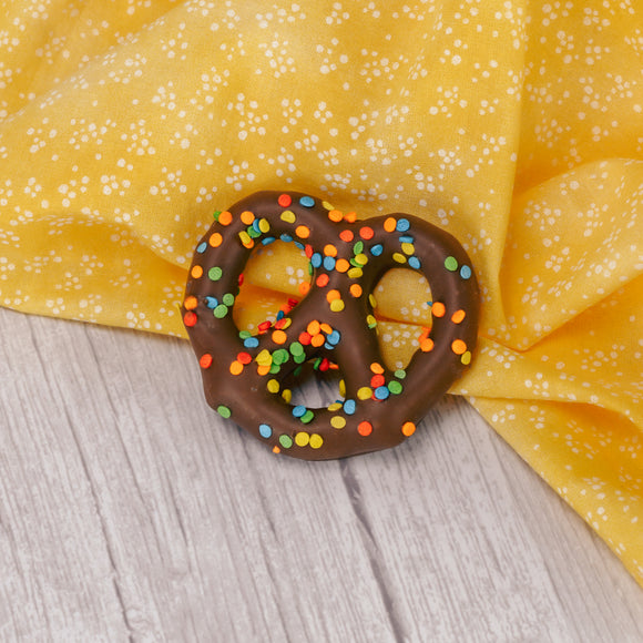 a jumbo pretzel covered in milk chocolate and topped with summer sprinkles on top.