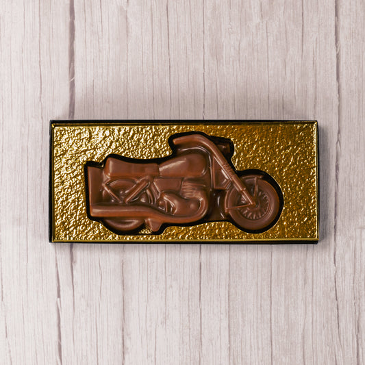 A motorcycle made of smooth milk chocolate is placed in a box with a clear lid, ready to be given as a gift to all of your motorcycle enthusiasts!