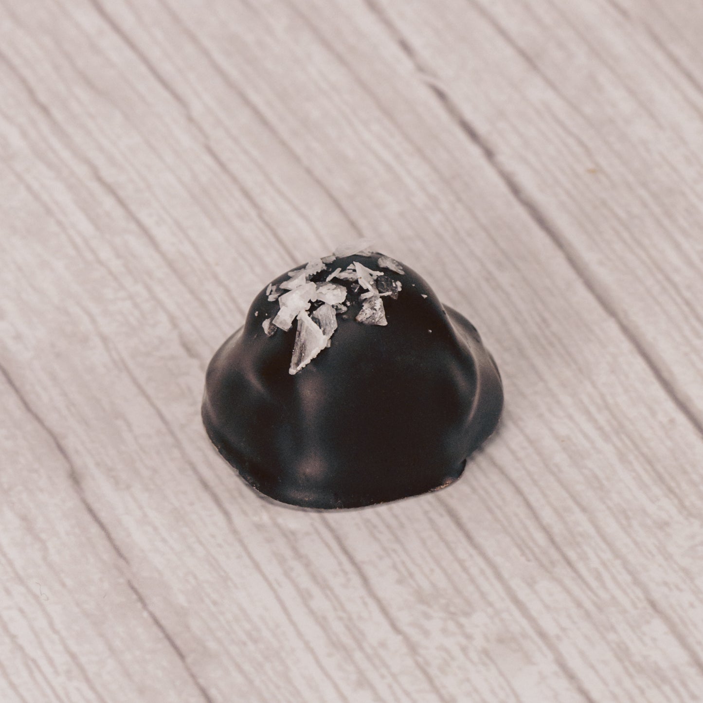 chewy caramel center dipped in dark chocolate and sprinkled with sea salt on top in a clear quarter pound rectangle tube