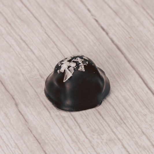 chewy caramel center dipped in dark chocolate and sprinkled with sea salt on top in a clear quarter pound rectangle tube