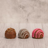 Marie's truffles made only five times a year that are made with cream and butter and have a mouse fluffy center. A box of 12, choose between Chocolate with white drizzle icing, chocolate with crushed pecans or raspberry with pink icing drizzle.