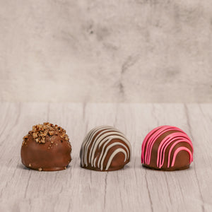 Marie's truffles made only five times a year that are made with cream and butter and have a mouse fluffy center. A box of 6 choose between Chocolate with white drizzle icing, chocolate with crushed pecans or raspberry with pink icing drizzle.