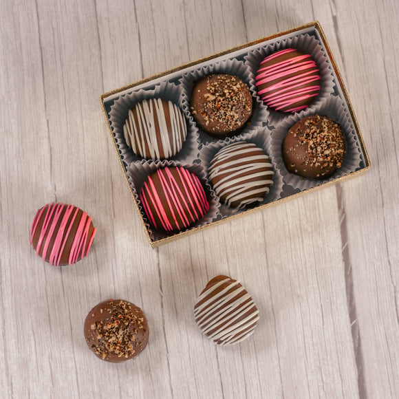 Marie's truffles made only five times a year that are made with cream and butter and have a mouse fluffy center. A box of 6 choose between Chocolate with white drizzle icing, chocolate with crushed pecans or raspberry with pink icing drizzle.
