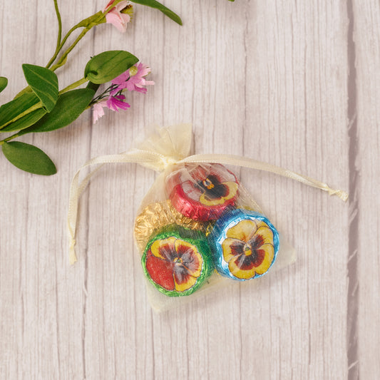 five milk chocolate foil wrapped pansies in an ivory gauzy pouch
