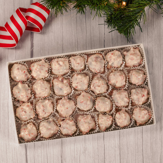 a pound of chocolate cream center covered in white coating with peppermint crunch pieces