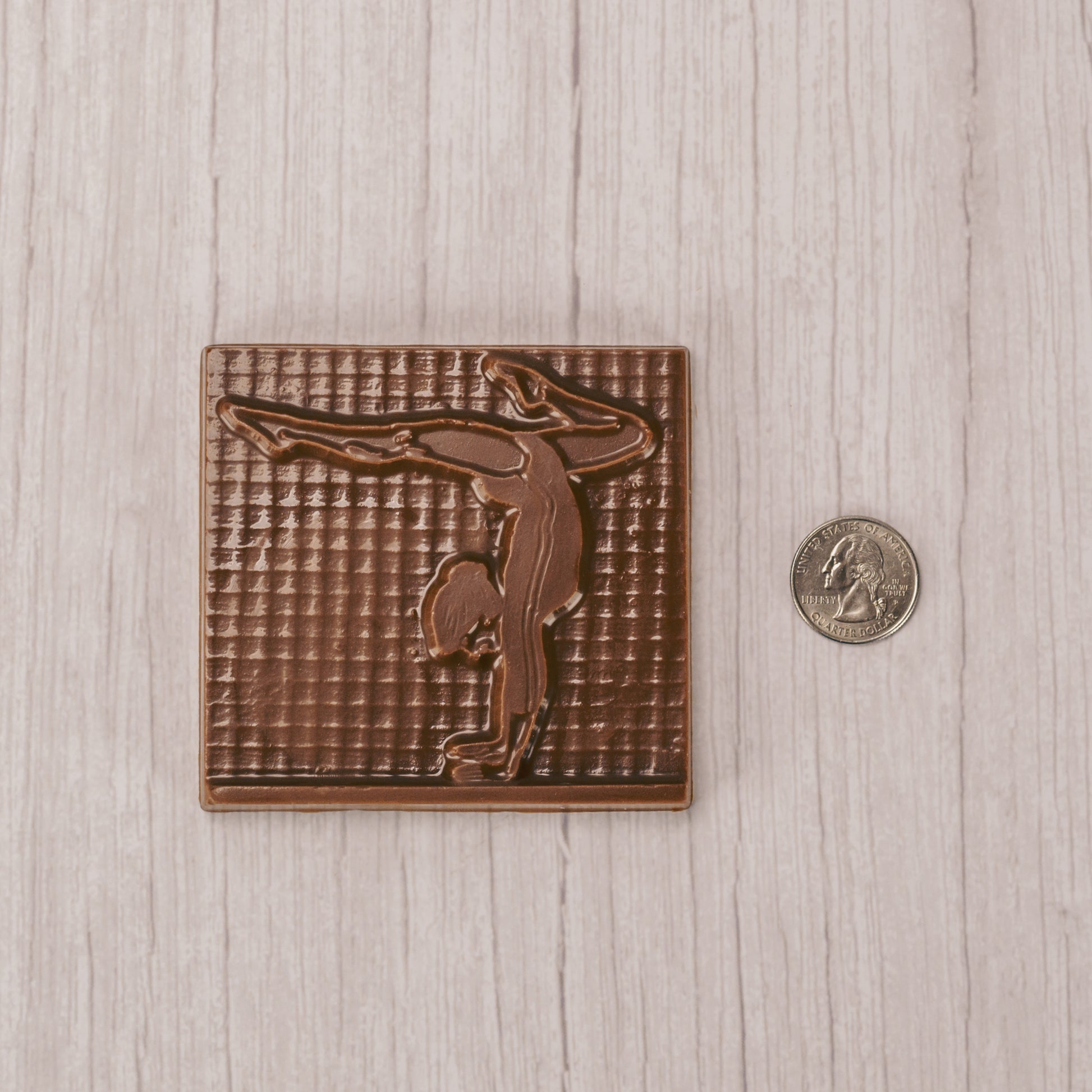 A square plaque of a gymnast in smooth milk chocolate.