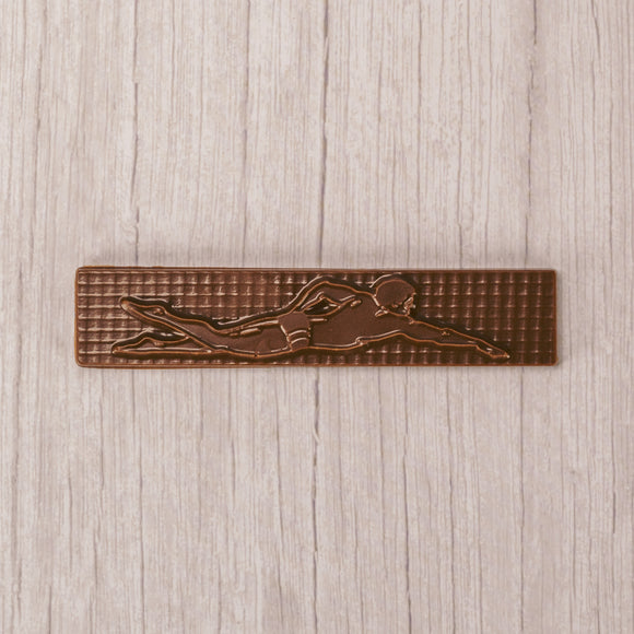 a long plaque of a swimmer in mid stroke in smooth milk chocolate.