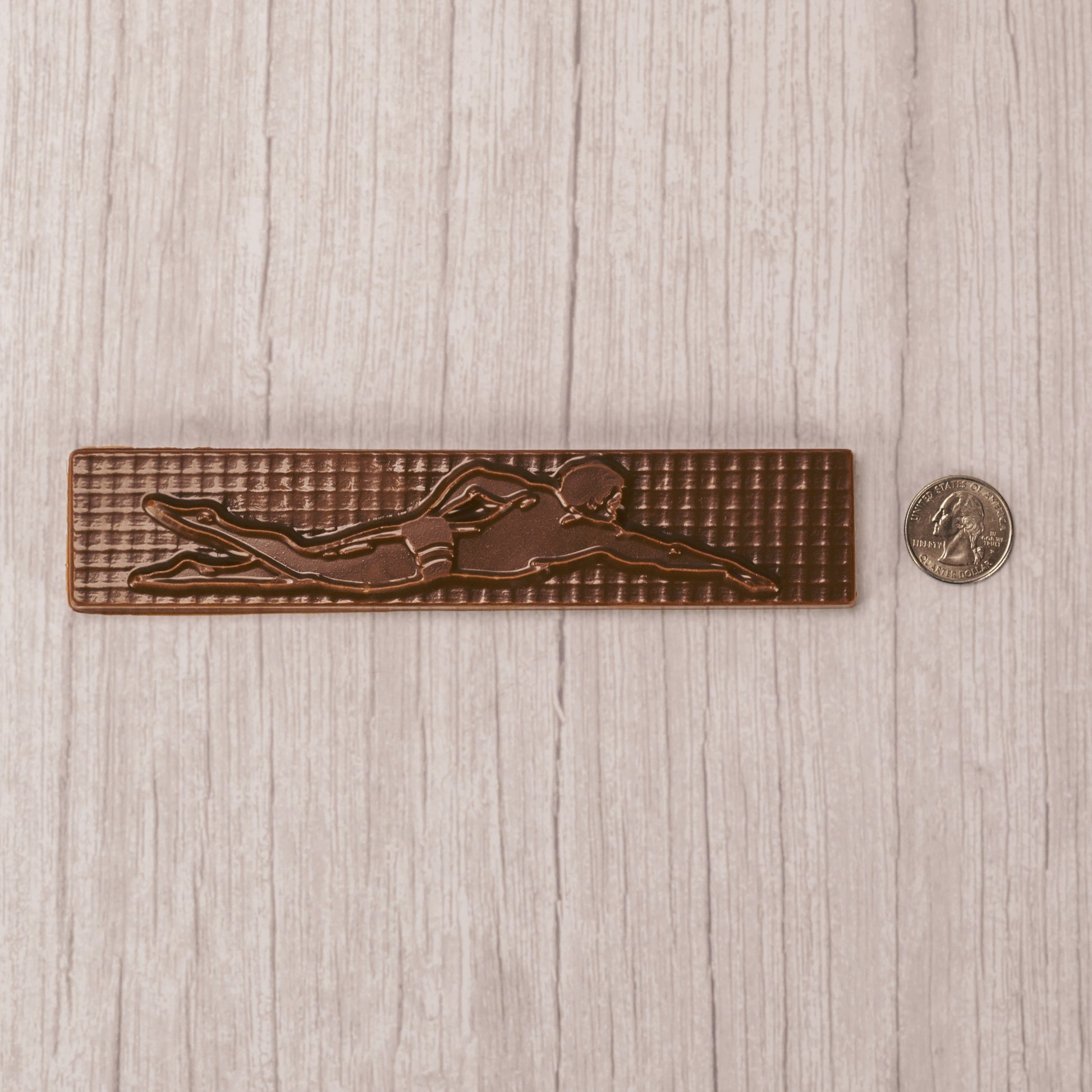 a long plaque of a swimmer in mid stroke in smooth milk chocolate.