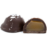 chewy caramel center dipped in dark chocolate and sprinkled with sea salt on top in a clear quarter pound rectangle tube